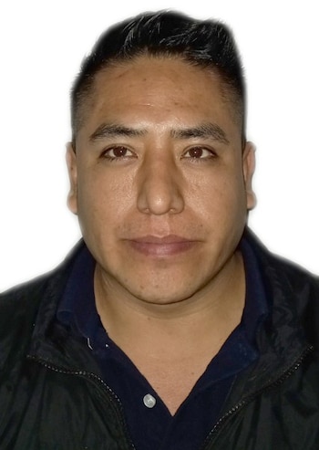 Retrato de primer plano de un hombre con cabello corto oscuro, camisa azul marino y casaca negra sobre un fondo blanco
