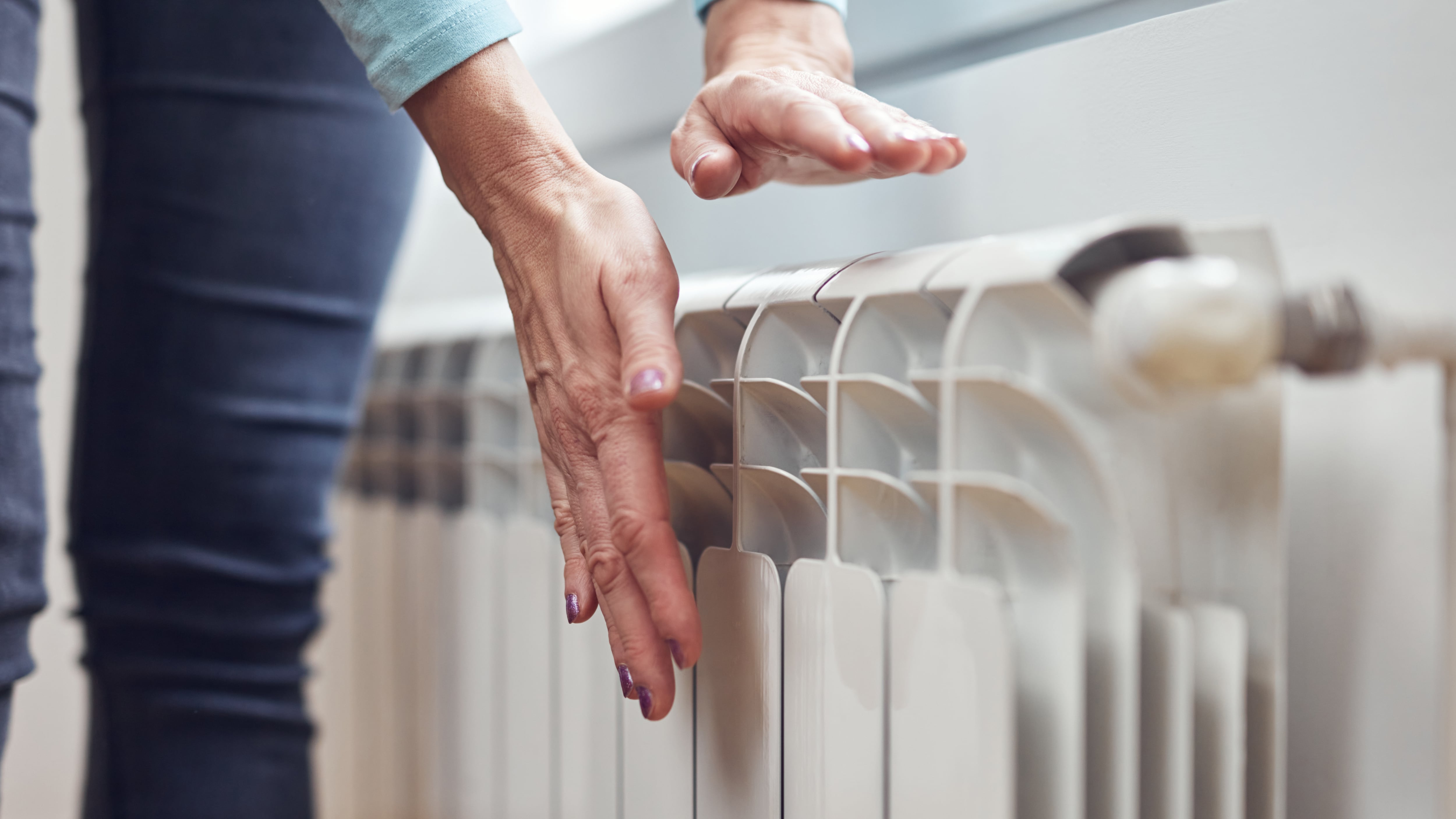 Una mujer comprueba la temperatura de su radiador. (AdobeStock)