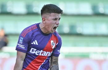 Un futbolista con camiseta morada de River Plate grita con la boca abierta frente a la tribuna del estadio