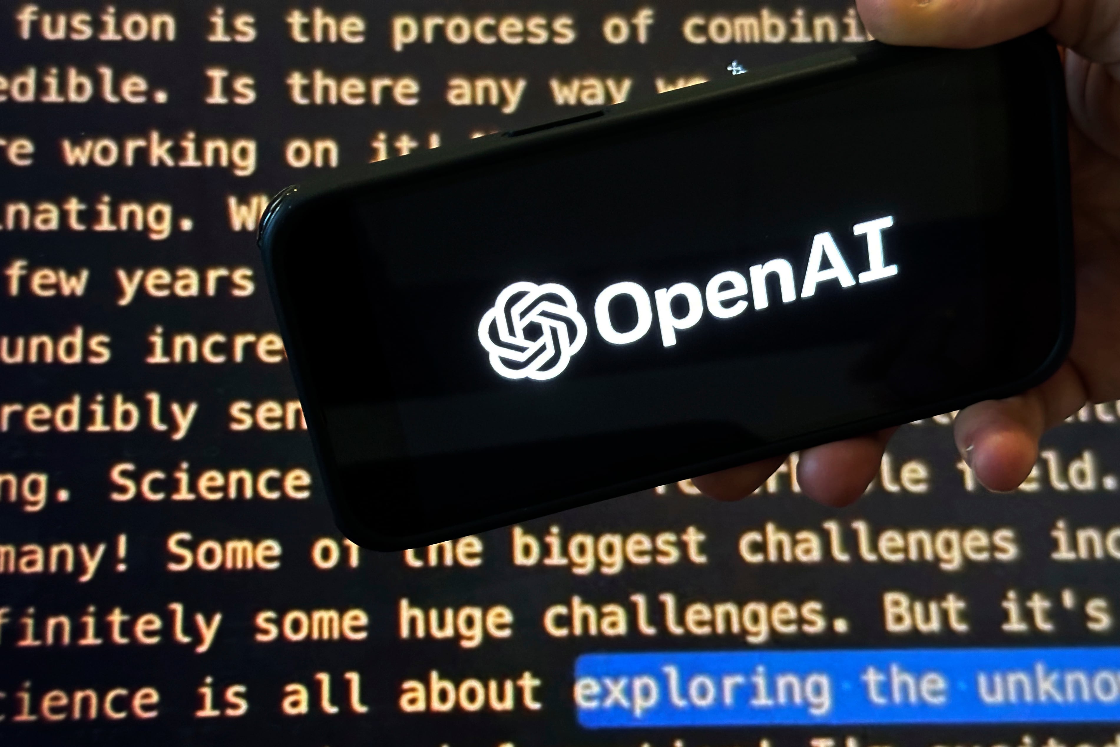 El logo de OpenAI en un teléfono celular frente a una pantalla que muestra el website de la compañía, en Nueva York el 21 de noviembre del 2023. (AP foto/Peter Morgan)