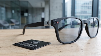 Gafas de marco negro con lente de cámara y luz roja en la patilla, situadas junto a una placa negra con el texto Grabación autorizada.