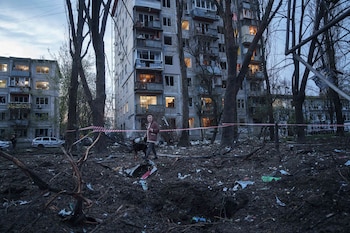 Una mujer camina con su perro entre los escombros de una vivienda dañada en Kiev. El ataque destruyó al menos 17 edificios de apartamentos en la capital. (AP Photo/Evgeniy Maloletka)