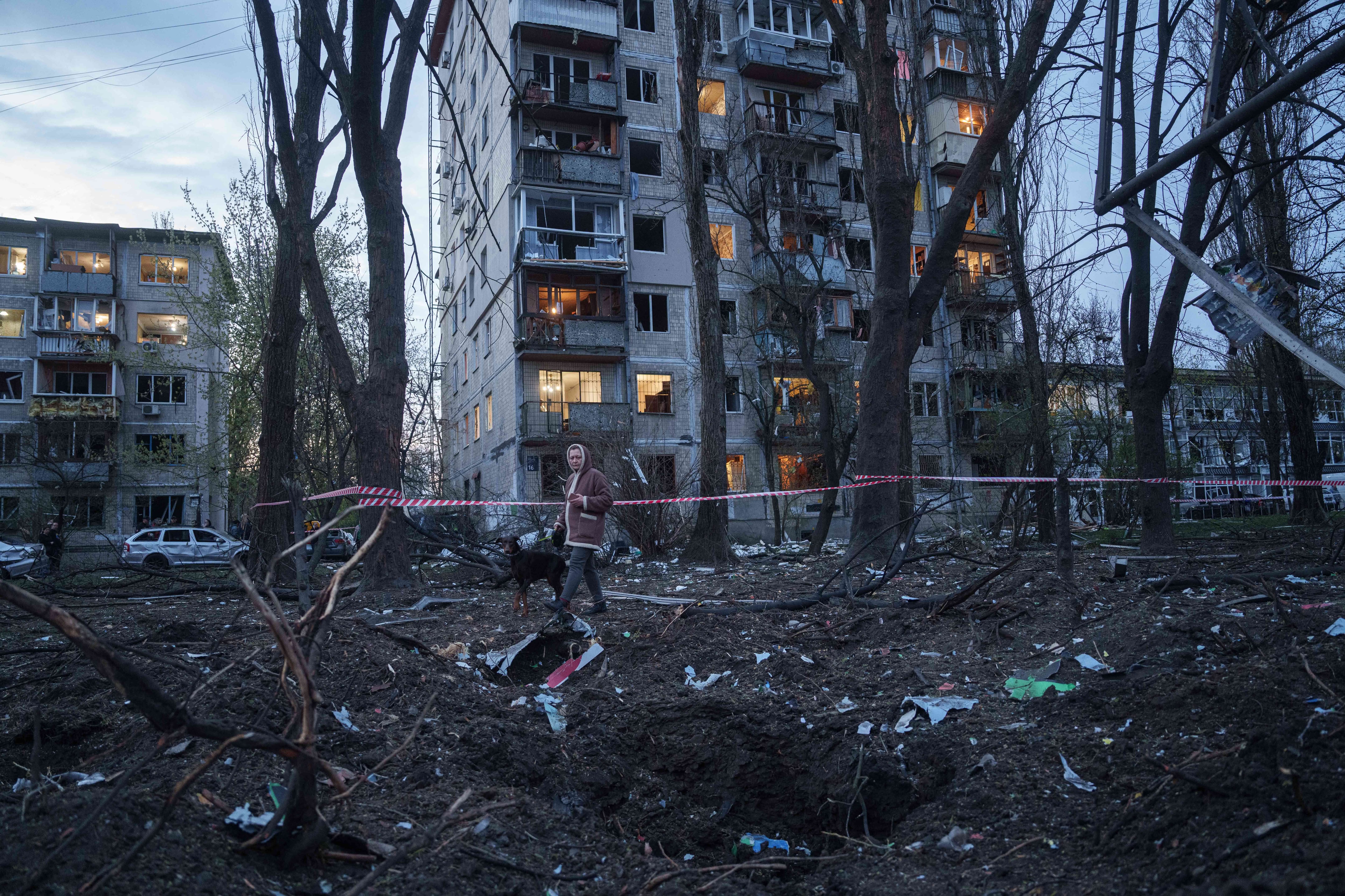 Una mujer camina con su perro entre los escombros de una vivienda dañada en Kiev. El ataque destruyó al menos 17 edificios de apartamentos en la capital. (AP Photo/Evgeniy Maloletka)