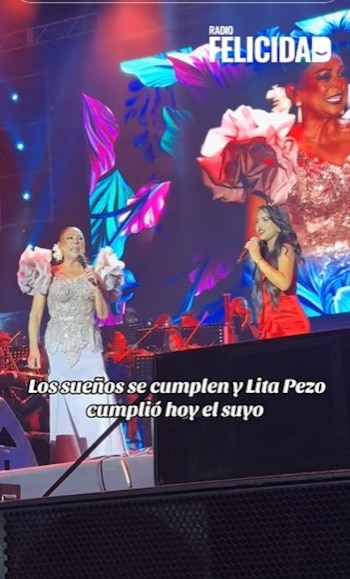 Isabel Pantoja, vestida de plateado, y Lita Pezo, de rojo, cantando en un escenario con luces de colores y pantalla de fondo