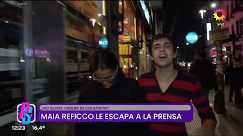 Una mujer con anteojos agacha la cabeza junto a un joven con camiseta a rayas rojas en una acera de noche