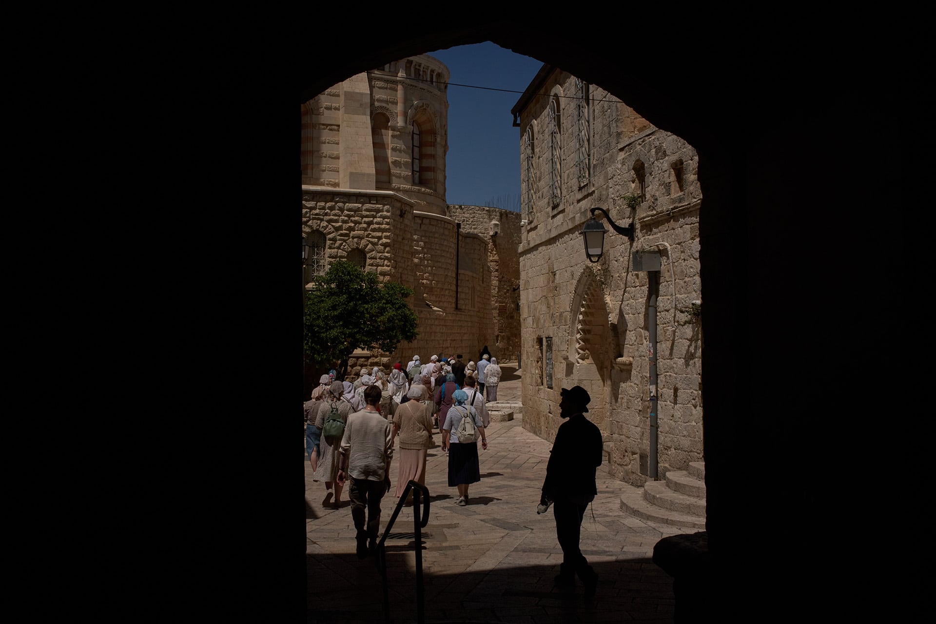 Peregrinos caminan por una antigua calle empedrada en la Ciudad Vieja de Jerusalén, pasando cerca de la Iglesia del Santo Sepulcro bajo un cielo despejado. (AP)