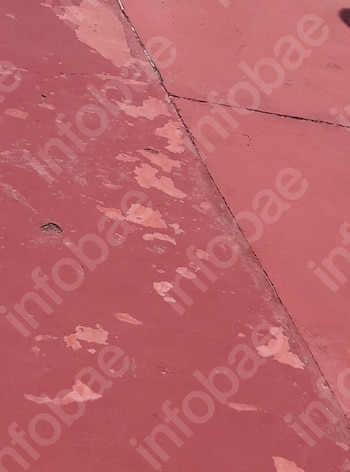 Primer plano de una superficie de color rojo con pintura descascarada, múltiples grietas y varias manchas irregulares por deterioro