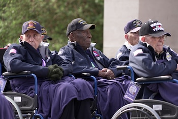 Calvin Shiner (centro), de 102 años y que fue seleccionado en 1943 para ingresar en una unidad de construcción de soldados negros en el ejército de Estados Unidos, y otros veteranos de la Segunda Guerra Mundial, asisten a un acto de conmemoración el 2 de junio de 2025 en Colleville-sur-Mer, en el cementerio estadounidense de Normandía, en vísperas del aniversario del Día D. (AP Foto/John Leicester)