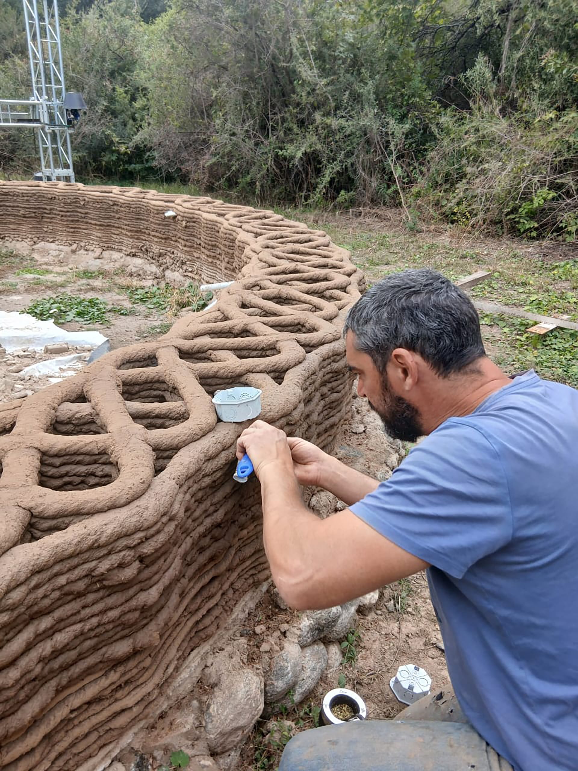 La estructura metálica de cuatro metros de altura deposita capa por capa una mezcla de arcilla, arena, paja y fibras vegetales para dar forma a las paredes de la vivienda
