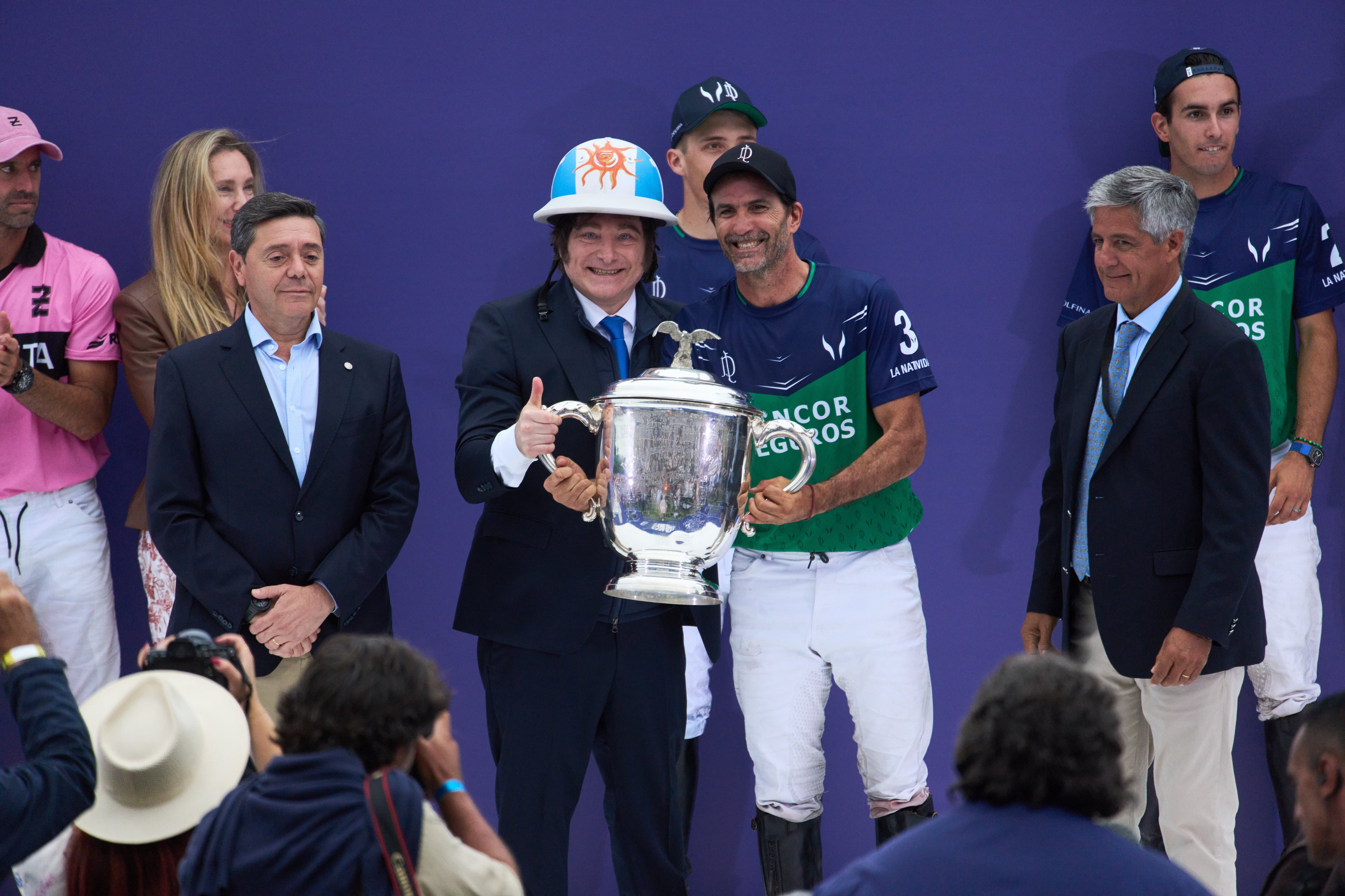 Argentina's President Javier Milei, center left, hands a trophy to polo player Adolfo Cambiaso of La Natividad La Dolfina during the Palermo Open awards ceremony in Buenos Aires, Argentina, Sunday, Dec. 7, 2025. (AP Photo/Rodrigo Abd)