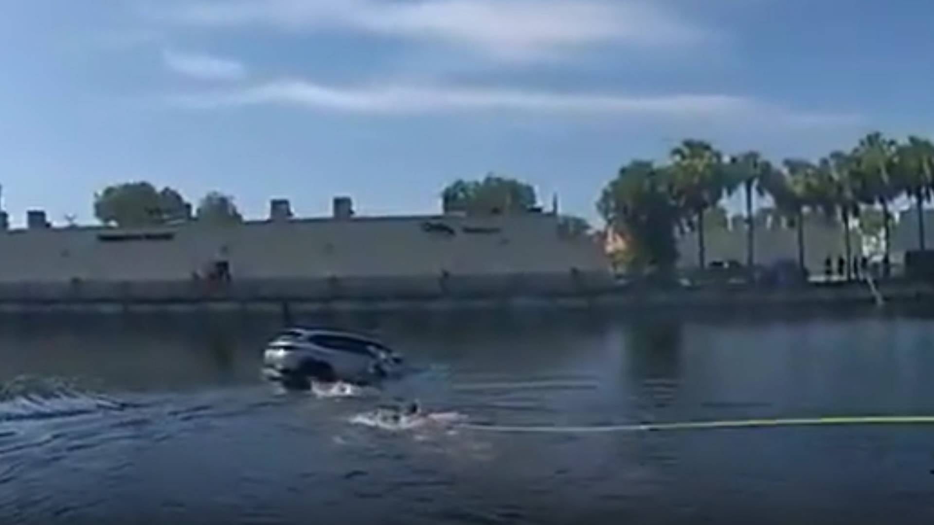 El momento exacto en que dos agentes del BSO y un bombero rescatan a la anciana del canal. La operación completa demoró apenas un minuto antes de que el vehículo se hundiera por completo (Broward Sheriff’s Office)