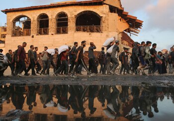 Palestinos caminan cargando suministros de