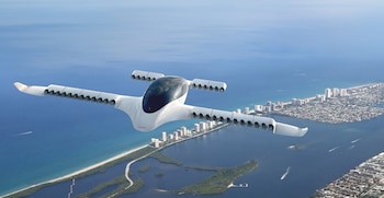Un avión Lilium eVTOL blanco vuela sobre la costa de Florida, con una ciudad costera y el océano azul visible