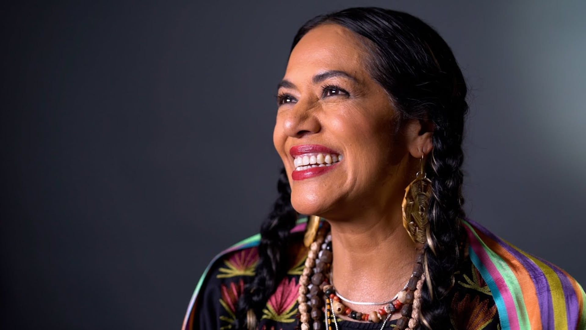 La cantante mexicana Lila Downs sonríe, luciendo un atuendo tradicional y accesorios, personificando el mensaje indígena que llevó al Mundial 2026. (YouTube: Lila Downs)