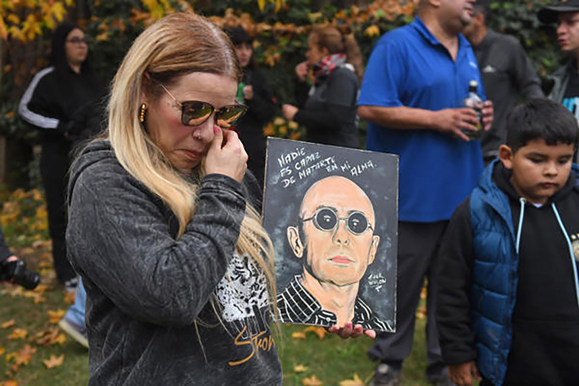 Dos fanáticos se congregan frente a un impactante estandarte con la imagen del Indio Solari, rindiendo homenaje en su velorio en Avellaneda. Foto: EFE