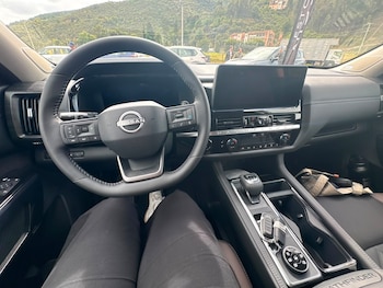 Vista desde el asiento del conductor hacia el volante con el logotipo de Nissan, la pantalla del tablero, la consola central y las llaves del auto