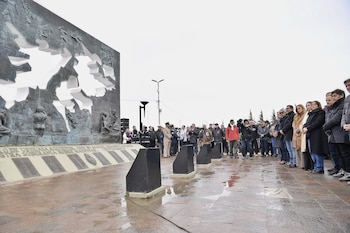 Um grupo de pessoas, incluindo um veterano das Malvinas com medalha e boné da Marinha Argentina, e um homem de jaqueta escura, participa de um evento ao ar livre