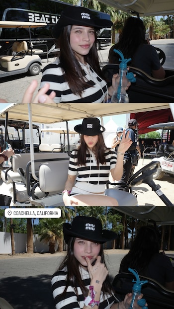 Emilia Mernes, con sombrero negro "Miu Miu" y blusa de rayas blancas y negras, sentada en un carrito de golf en un día soleado en Coachella, sosteniendo una botella de agua