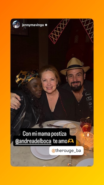 Tres personas posan sonriendo en una mesa de restaurante. Una mujer con pañuelo de leopardo, otra de cabello claro y un hombre con barba y sombrero