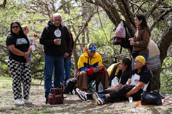 Grupo de seis personas en un área boscosa. Tres mujeres sentadas, dos hombres y una mujer de pie. Una mujer lleva gorra y chaqueta de Venezuela. Se observan mochilas y botellas