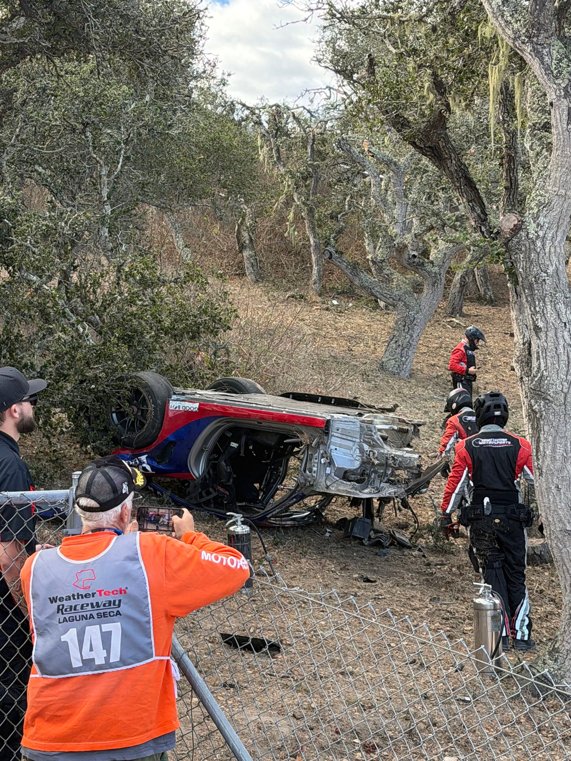 Un automóvil de carreras descansa volcado fuera de la pista tras un accidente en la competencia Porsche Sprint Challenge en el circuito de Laguna Seca.