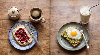 Dos platos sobre madera: uno con tostada de mermelada, café y azucarera; el otro con tostada de palta y huevo frito junto a un batido.
