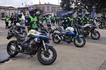 Un hombre en traje saluda a un policía con casco y chaleco reflectante junto a una fila de motocicletas