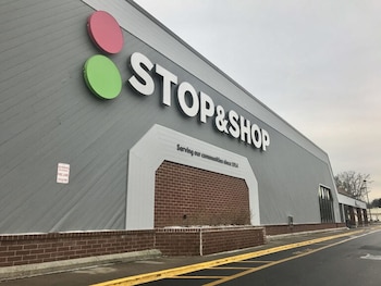 Edificio de pared gris con el letrero de Stop & Shop, una seccion de ladrillo rojo y lineas amarillas trazadas en el asfalto