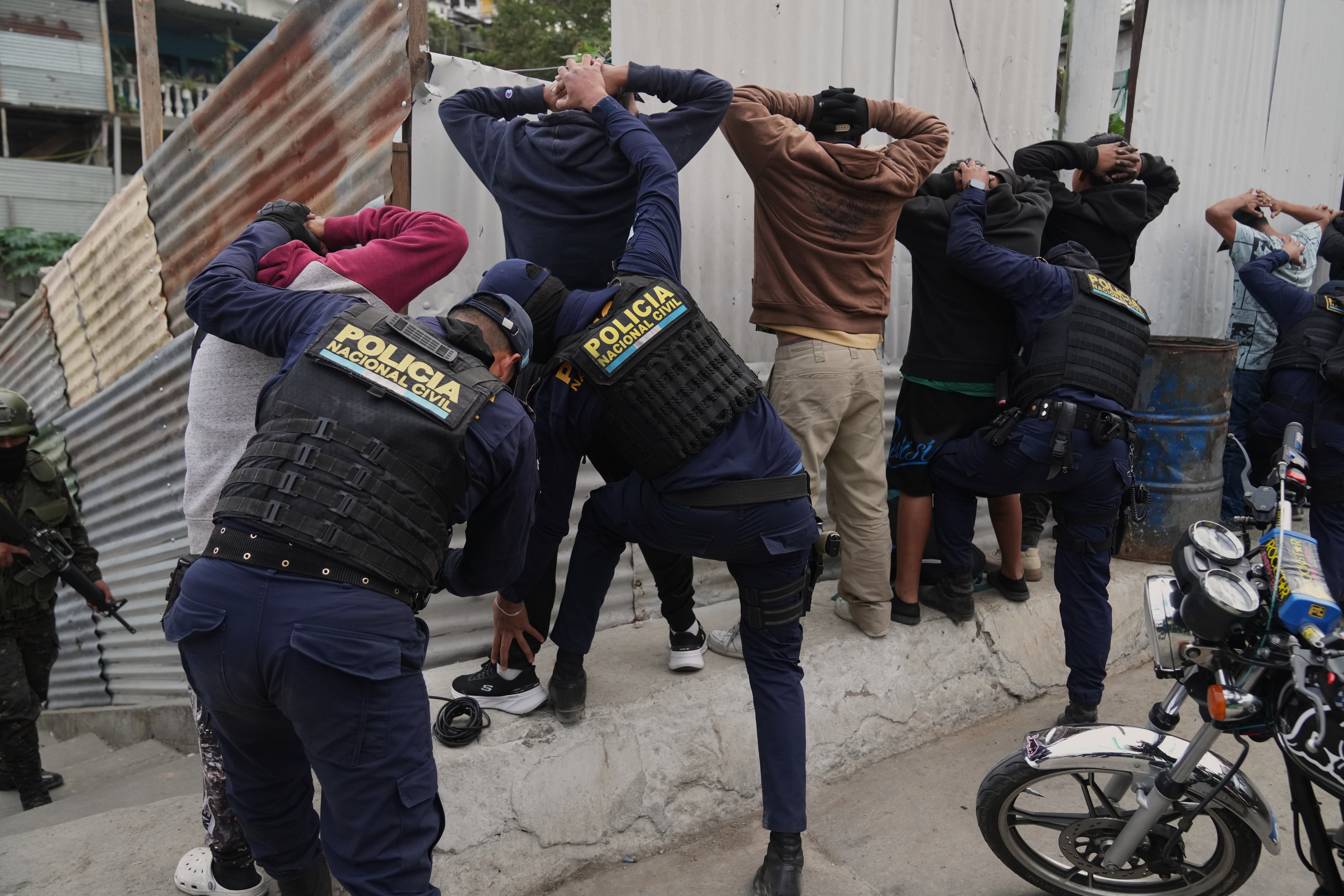Agentes de policía cachean a hombres durante el estado de emergencia del país, tras una escalada de violencia relacionada con pandillas, en las afueras de la Ciudad de Guatemala, el martes 20 de enero de 2026. (AP Foto/Moisés Castillo)