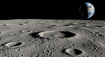 Superficie de la Luna con numerosos cráteres y rocas, bajo el espacio oscuro que muestra estrellas y el planeta Tierra iluminado parcialmente.