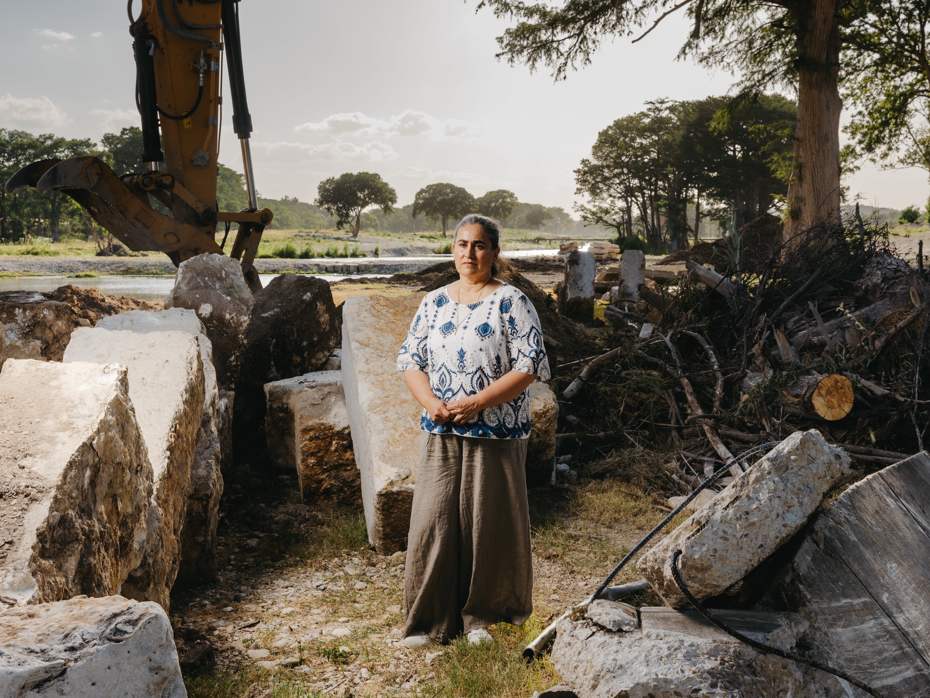 Lorena Guillén posa junto a maquinaria pesada y piedras utilizadas para reconstruir partes de su propiedad a lo largo del río Guadalupe en Ingram, Texas (Christopher Lee/The Washington Post)