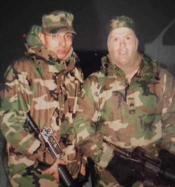 Dos hombres, incluido el exsargento Wilmer Trujillo, vestidos con uniformes militares de camuflaje, gorros y chaquetas, sostienen rifles