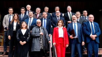 Hombres y mujeres con trajes formales y sastres permanecen de pie y alineados en las escaleras exteriores de un edificio