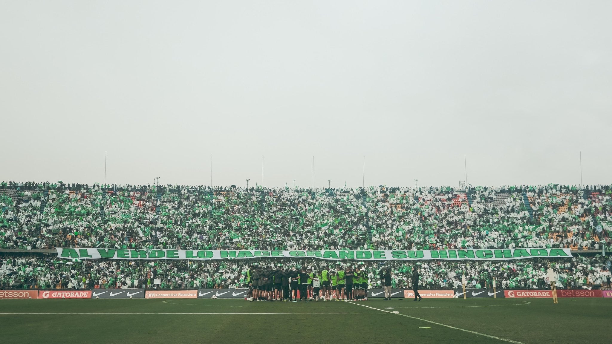 Los jugadores de Atlético Nacional en la mitad del Atanasio Girardot y de fondo la hinchada con una frase que dice Al verde lo hace grande su hinchada - crédito Atlético Nacional
