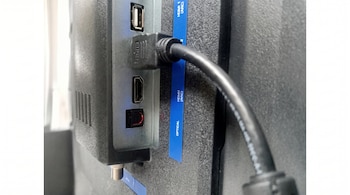 Parte trasera de un televisor con un cable HDMI conectado a un puerto HDMI, un puerto USB, un puerto de audio óptico y un conector coaxial.