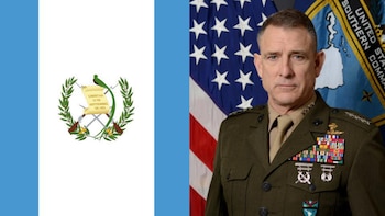 Primer plano de Francis Donovan, un oficial militar con uniforme verde oliva, frente a las banderas de Guatemala (izquierda) y Estados Unidos (derecha) y el emblema del Comando Sur de EE. UU