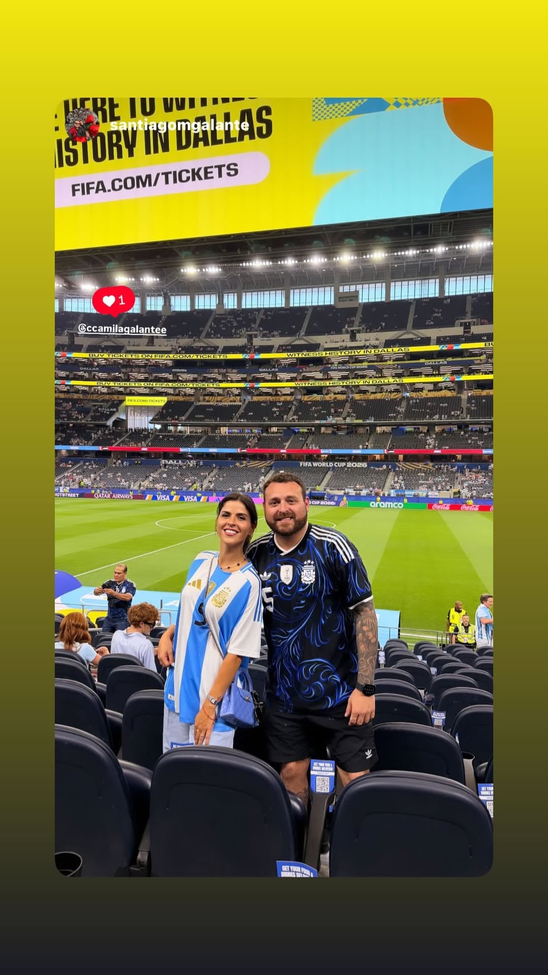 Camila Galante y Leandro Paredes posan en un estadio de Dallas, Estados Unidos, con camisetas de la selección argentina y pantallas que anuncian el Mundial 2026.
