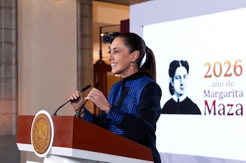 Claudia Sheinbaum en un pódium con el escudo de México y dos micrófonos, junto a una pantalla con un retrato de Margarita Maza
