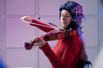 El sistema OPM-MEG, integrado en un casco ligero y una mochila, permitió registrar la actividad cerebral de los participantes mientras tocaban el violín (Foto: Universidad de Nottingham)
