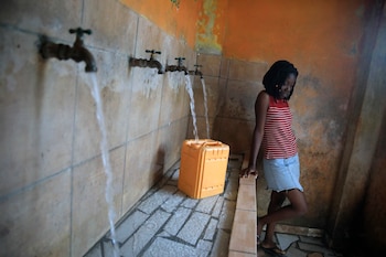 Una residente, sin agua potable en su casa, llena un contenedor en una fuente, en Puerto Príncipe, Haití, el 21 de marzo de 2023. (AP Foto/Odelyn Joseph)
