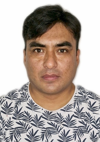 Retrato de frente de un hombre con cabello oscuro y camiseta blanca con patrón de hojas sobre un fondo blanco