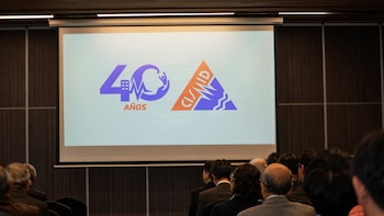 Logotipo en pantalla blanca: el número 40 con un edificio, latido y persona, y el texto 'AÑOS'. A su lado, un triángulo con 'CISMID' y ondas. Asistentes de espalda