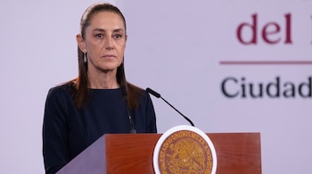 Claudia Sheinbaum de pie detrás de un pódium de madera con el escudo nacional de México y dos micrófonos.