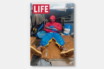 Portada de la revista LIFE con un pescador en ropa impermeable roja y azul sentado en la cubierta de un barco mientras sostiene un pez