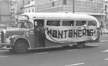 Fotografía en blanco y negro de un autobús urbano antiguo en una calle. Un cartel con "MONTONEROS" cuelga de su lateral. Se ven personas en la puerta y ventanas
