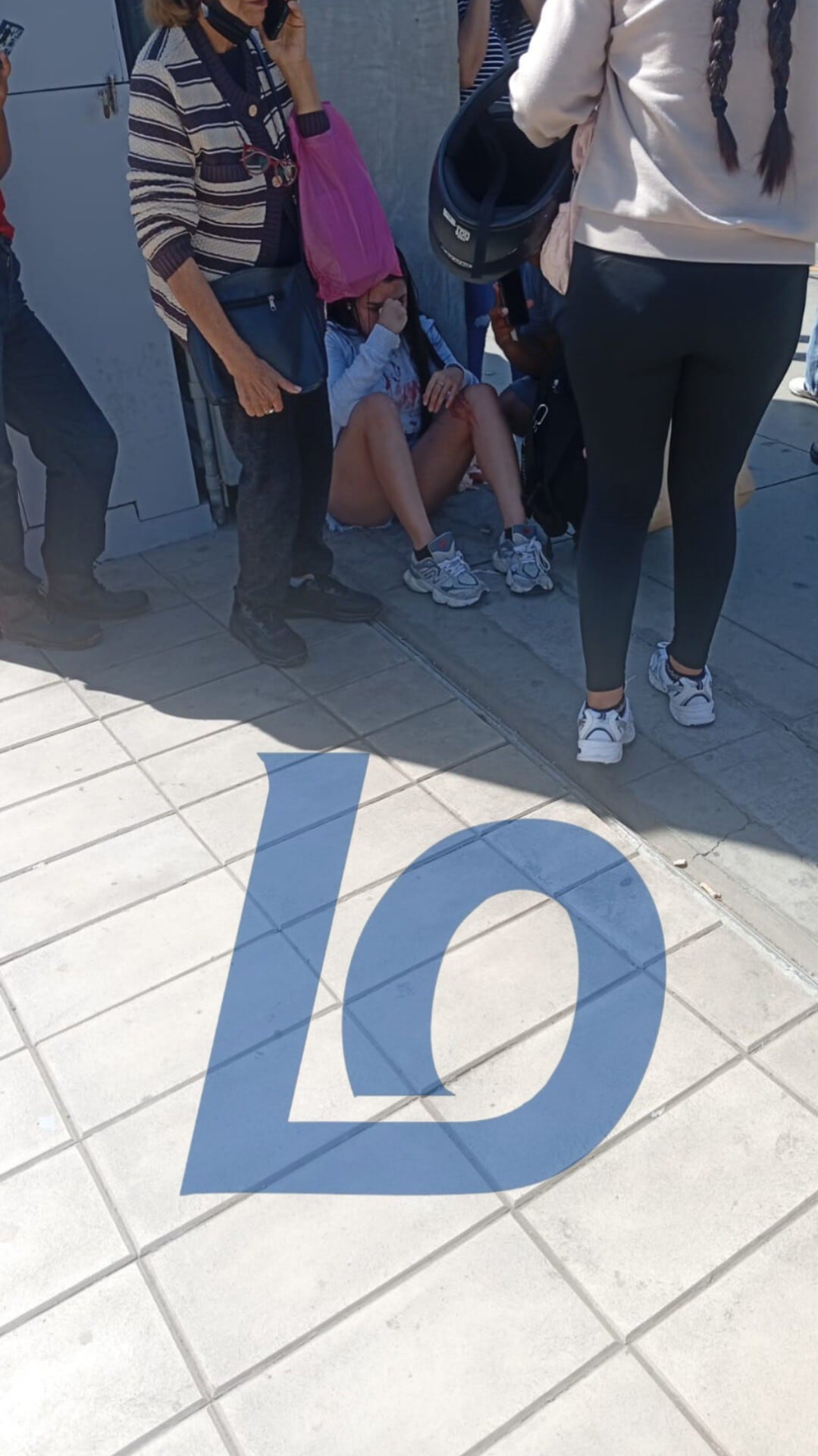 Una mujer recibe ayuda de una transeúnte, quien ingeniosamente le coloca una bolsa rosa en la cabeza, tras sufrir una caída y herirse la rodilla en plena calle. (Ica Rec Noticias)