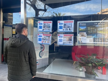 Un hombre mira anuncios de pisos en veta en una inmobiliaria.