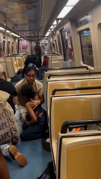 Interior de un vagón de tren de MARTA con asientos beige y piso azul. Varias personas sentadas o en el suelo, algunas consolándose mutuamente