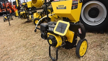Una trituradora de madera Champion Power Equipment amarilla y negra con ruedas y detalles de motor, exhibida sobre césped seco en un día soleado