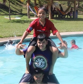 Carlos Mauricio Gómez (segundo en la foto) nació el 27 de septiembre de 1994 en San Sebastián, departamento de San Vicente, El Salvador. Construyó su carrera en internet a través de transmisiones de videojuegos en plataformas como Twitch, YouTube y Kick.